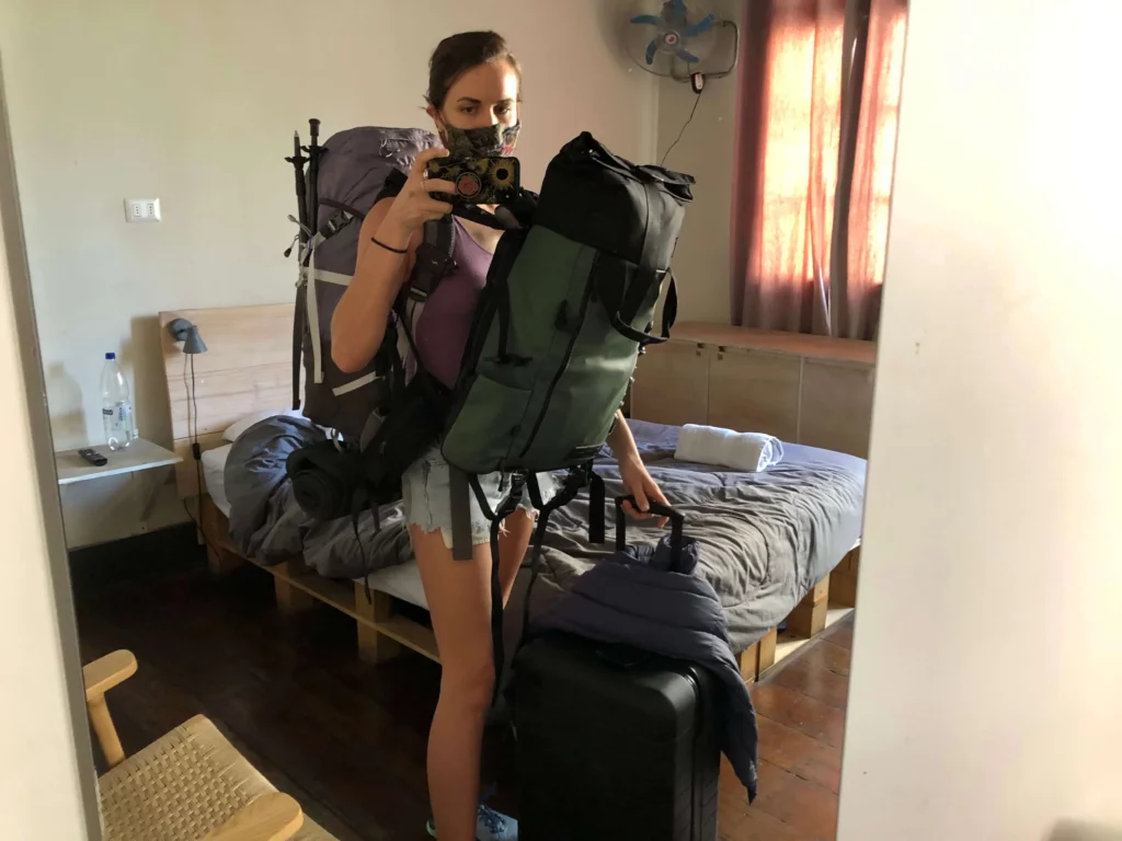 woman carrying several traveling bags backpacks
