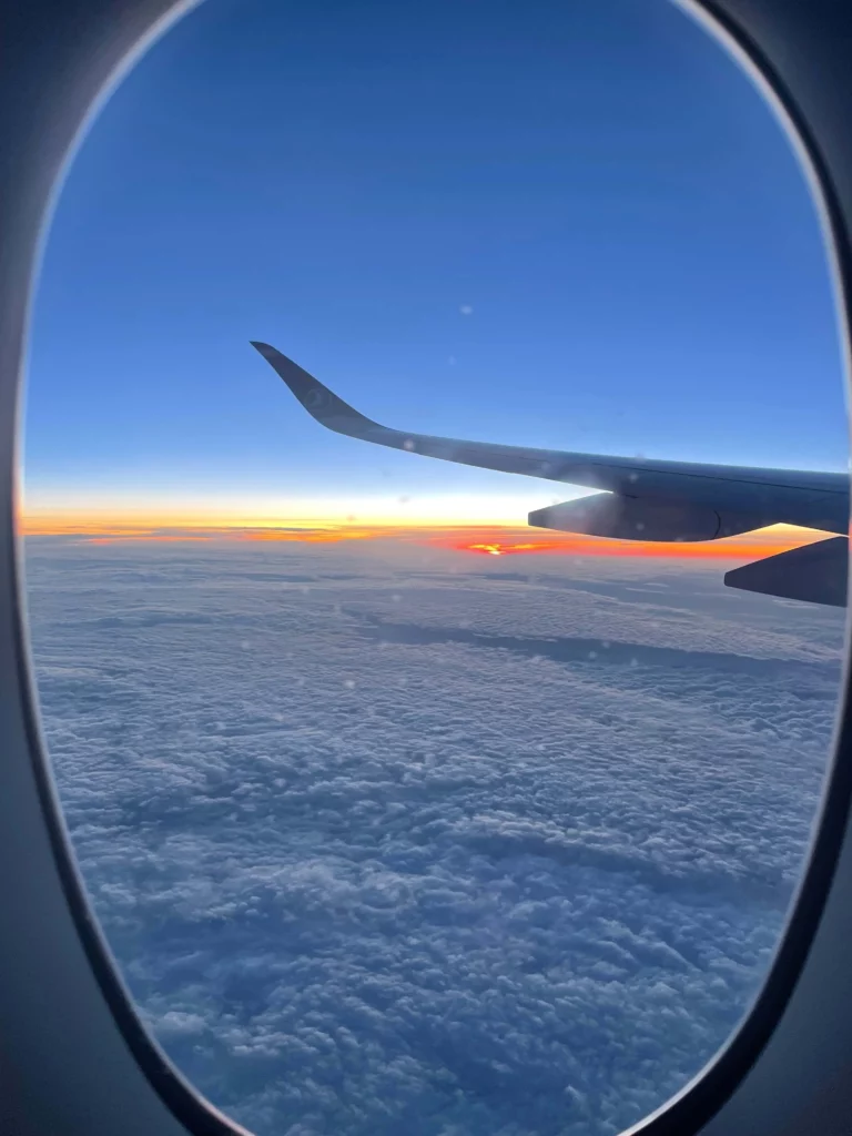 looking at sunrise from airplane window wing