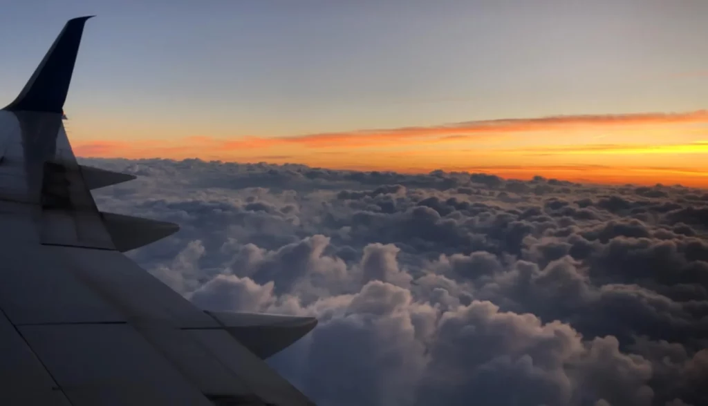 airplane wing over clouds orange sunset