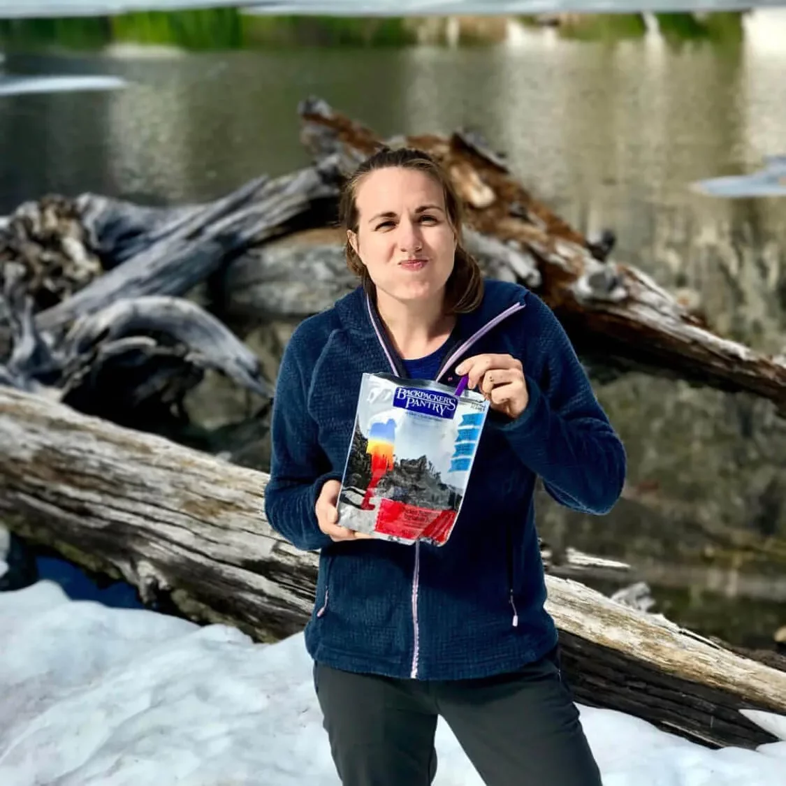 solo female traveler eating backpacking meal in nature