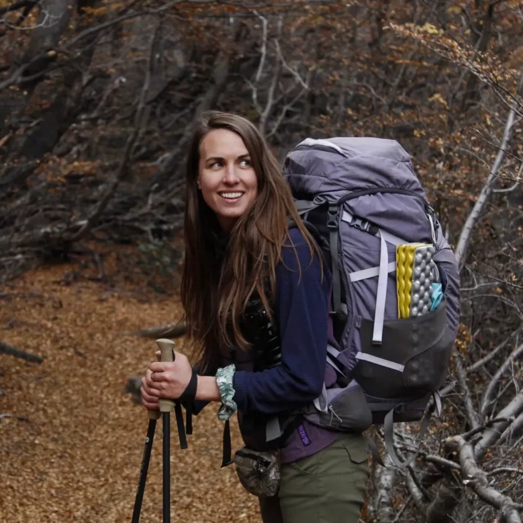 solo female hiker with backpack camping gear in forest