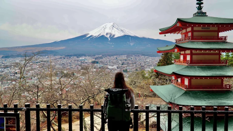 solo female traveler looking at mount fuji standing next to cheurito pagoda
