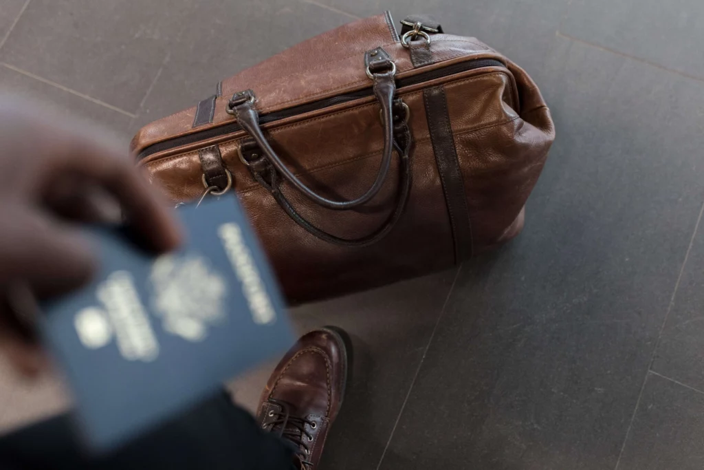 leather bag on floor man holding passport in hand