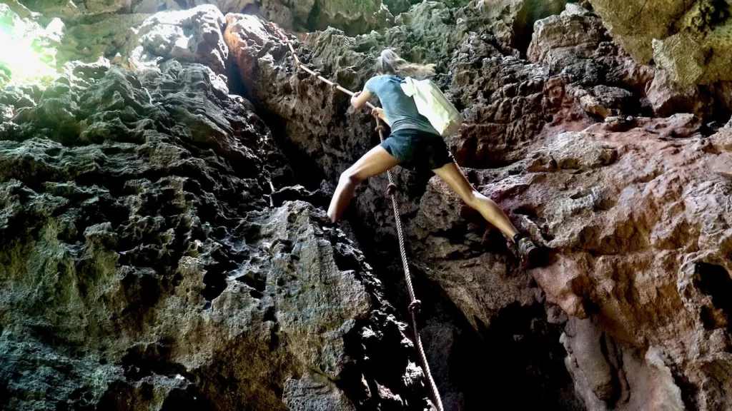 woman climbing rocks with rope railay