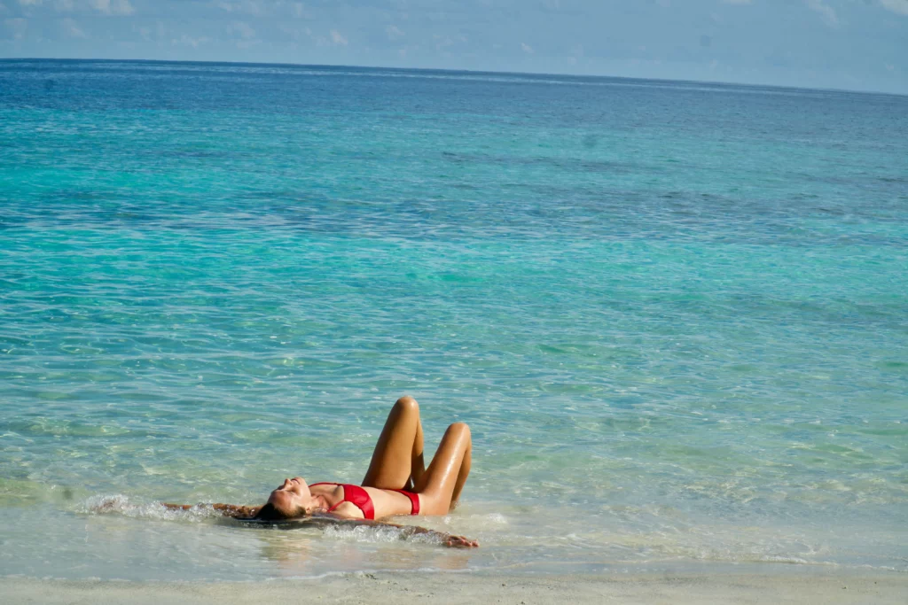 woman laying in turquoise water beach