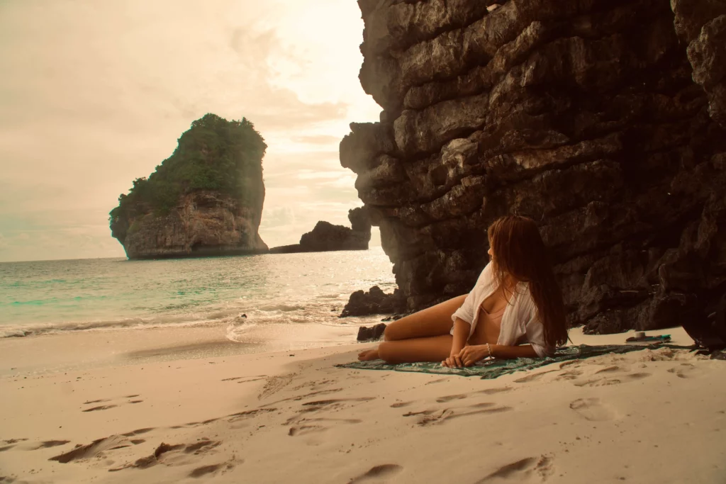 woman laying on beach thailand rock cliff