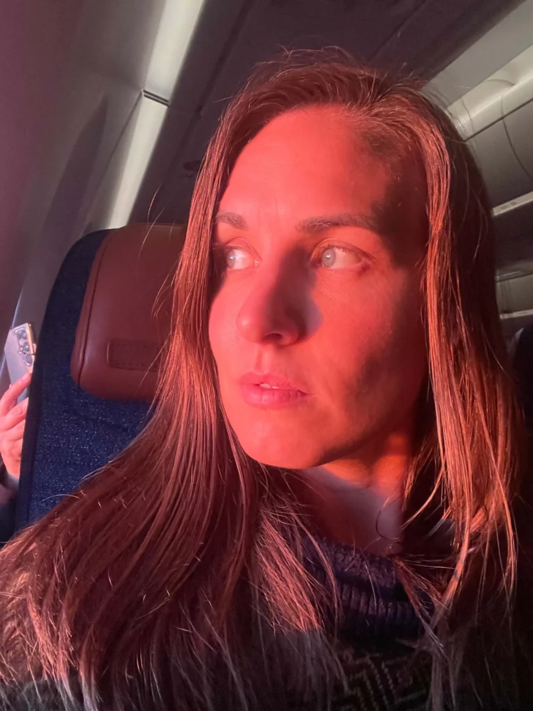 woman looking out window of airplane into sunset