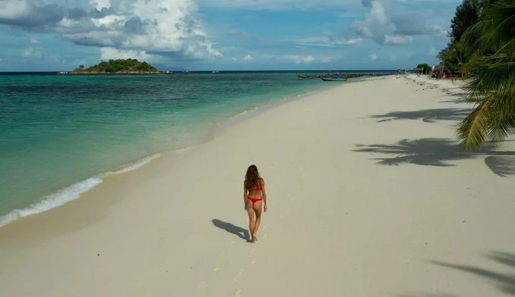 solo female traveler on white sand beach best times to visit thailand